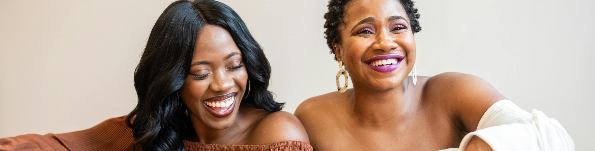 Two African American women laughing and enjoying each other's company indoors.